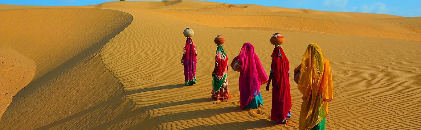 Indian women carrying heavy jugs of water on their head and walk