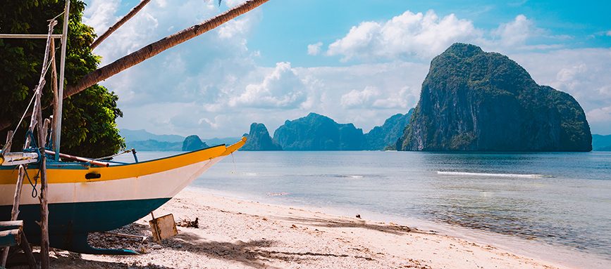 Banca boat on shore under palm trees.Tropical island scenic landscape. El-Nido, Palawan